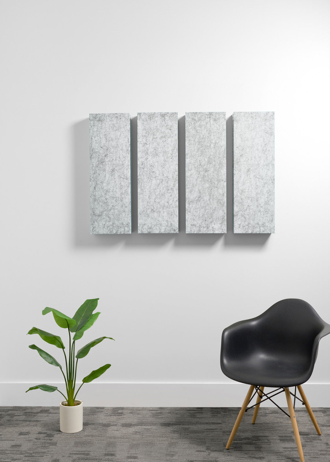 A modern interior scene with a four-panel wall art piece mounted on a white wall above a gray floor. The artwork consists of four vertical rectangular panels with a light gray marbled texture.