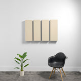 Four beige rectangular acoustic panels mounted on a white wall above a black chair and potted plant.