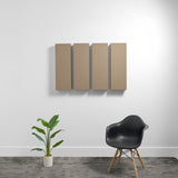 Four tan rectangular acoustic panels mounted on white wall above black chair and potted plant.