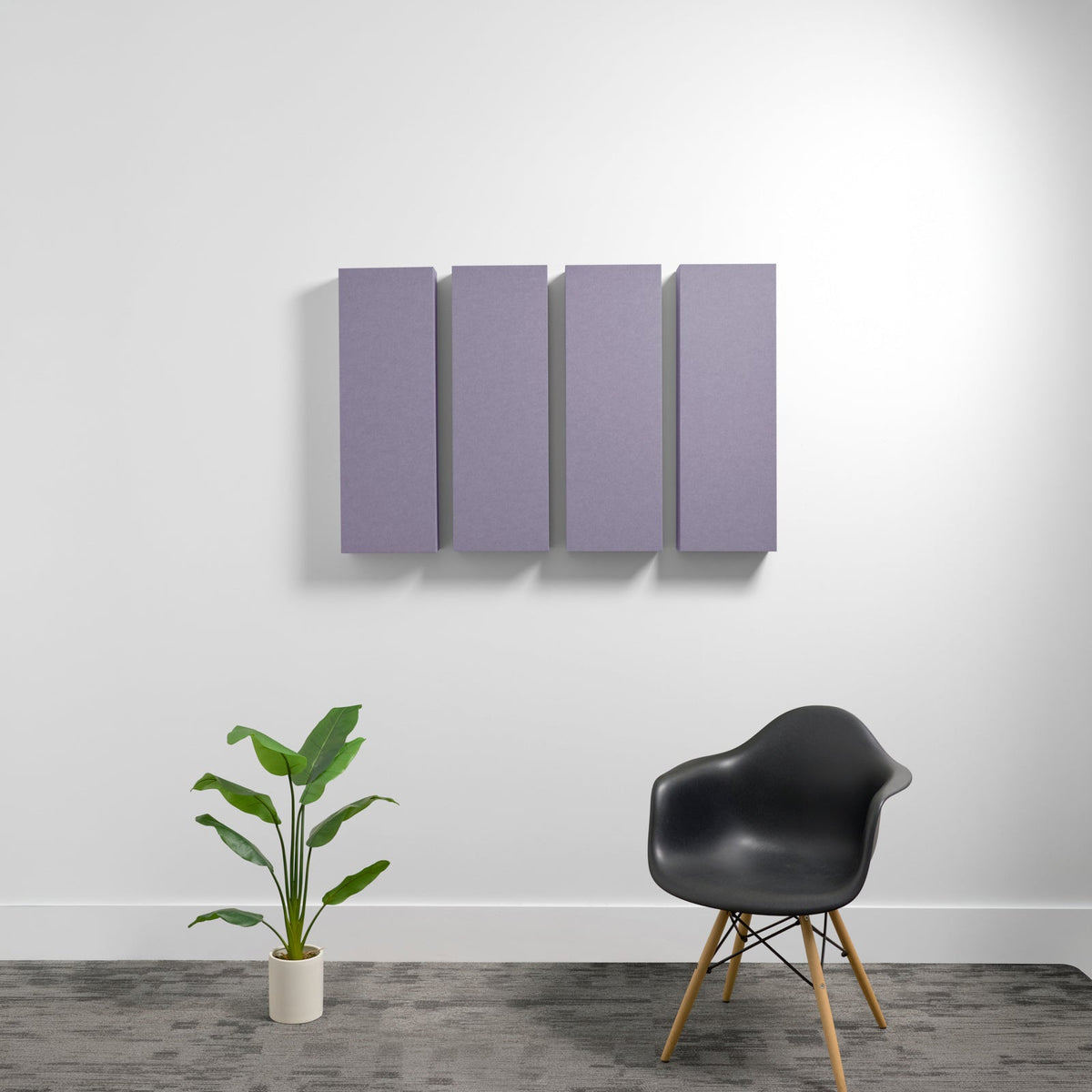 Four purple rectangular acoustic panels mounted on white wall above black chair and potted plant.