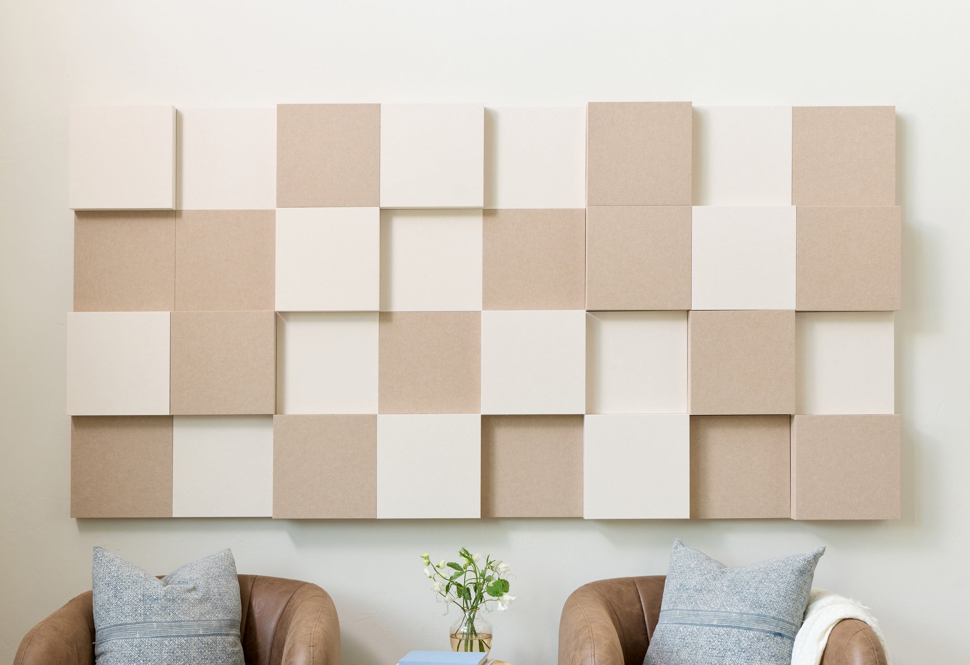 Ivory and Indigo colored 3D acoustic boxes on a white wall behind two maroon chairs