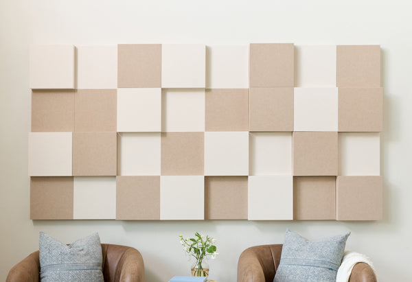 Cream and tan acoustic 3D boxes on a wall with chairs below