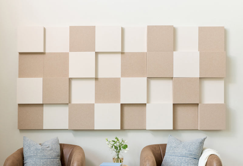 Cream and tan acoustic 3D boxes on a wall with chairs below