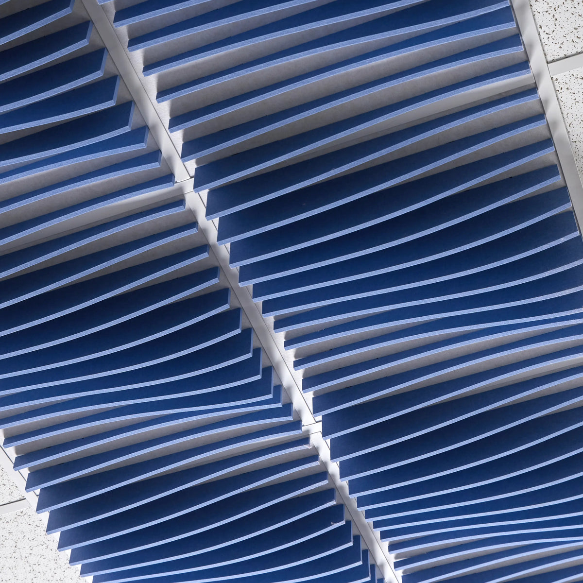 Close-up of blue Ripple felt drop ceiling tiles with deep 3D wave fins