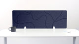 Navy blue desk divider with organic wavy line pattern, mounted on white desk with supports.