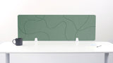 Green desk divider with organic wavy line pattern, mounted on white desk with supporting brackets.