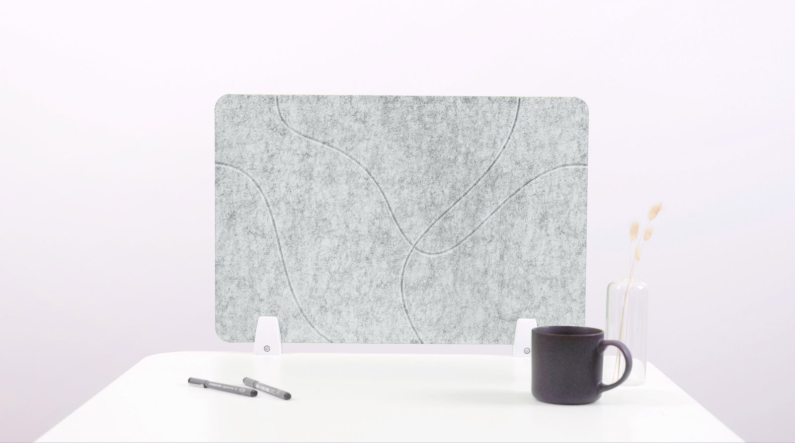 Felt screen protector on a white surface with a pen and mug