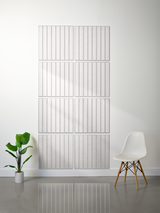Four light gray tiles arranged in a 2x2 grid, each with vertical parallel line engravings.