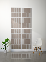 Eight taupe tiles with white engraved linear patterns arranged in offset configuration on wall.