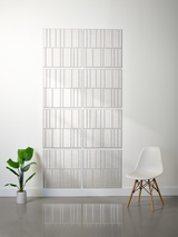 Eight light gray rectangular tiles with vertical engraved line patterns arranged in offset rows on a wall.