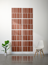 Eight terracotta tiles with white engraved offset stripe pattern arranged in a 2x4 grid on wall.