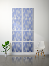 Eight blue tiles with white wavy line engraving arranged in a 2x4 grid on a wall.