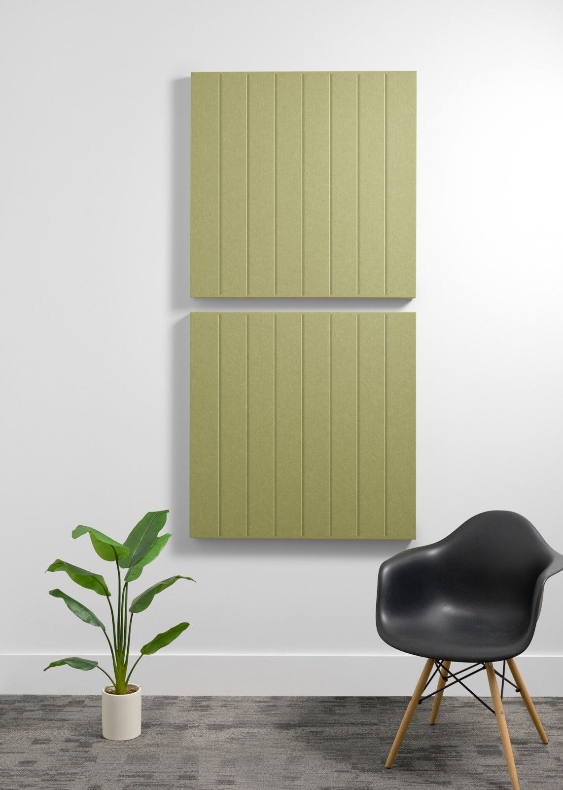 Two sage green 3D acoustic panels with vertical ribbed texture mounted on wall above black chair and potted plant.