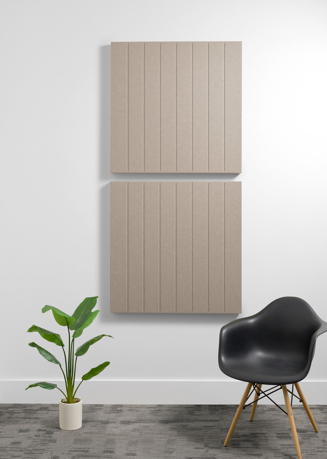 Two large beige acoustic wall panels with vertical ribbed texture mounted on wall above black chair and potted plant.