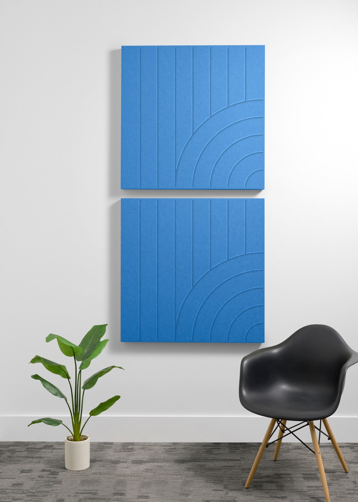 Two stacked blue acoustic panels with vertical lines and curved arc engravings mounted on wall.