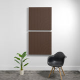 Two stacked brown acoustic panels with vertical line pattern and curved geometric engravings on white wall.
