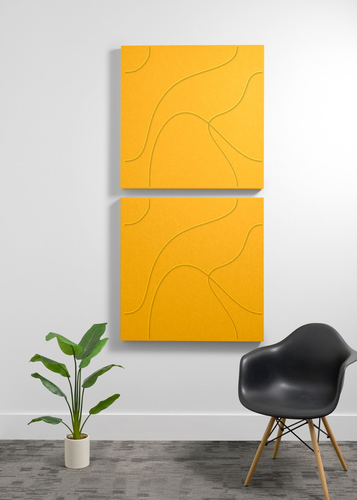 Two large yellow 3D acoustic panels with engraved curved line patterns mounted vertically on a wall.