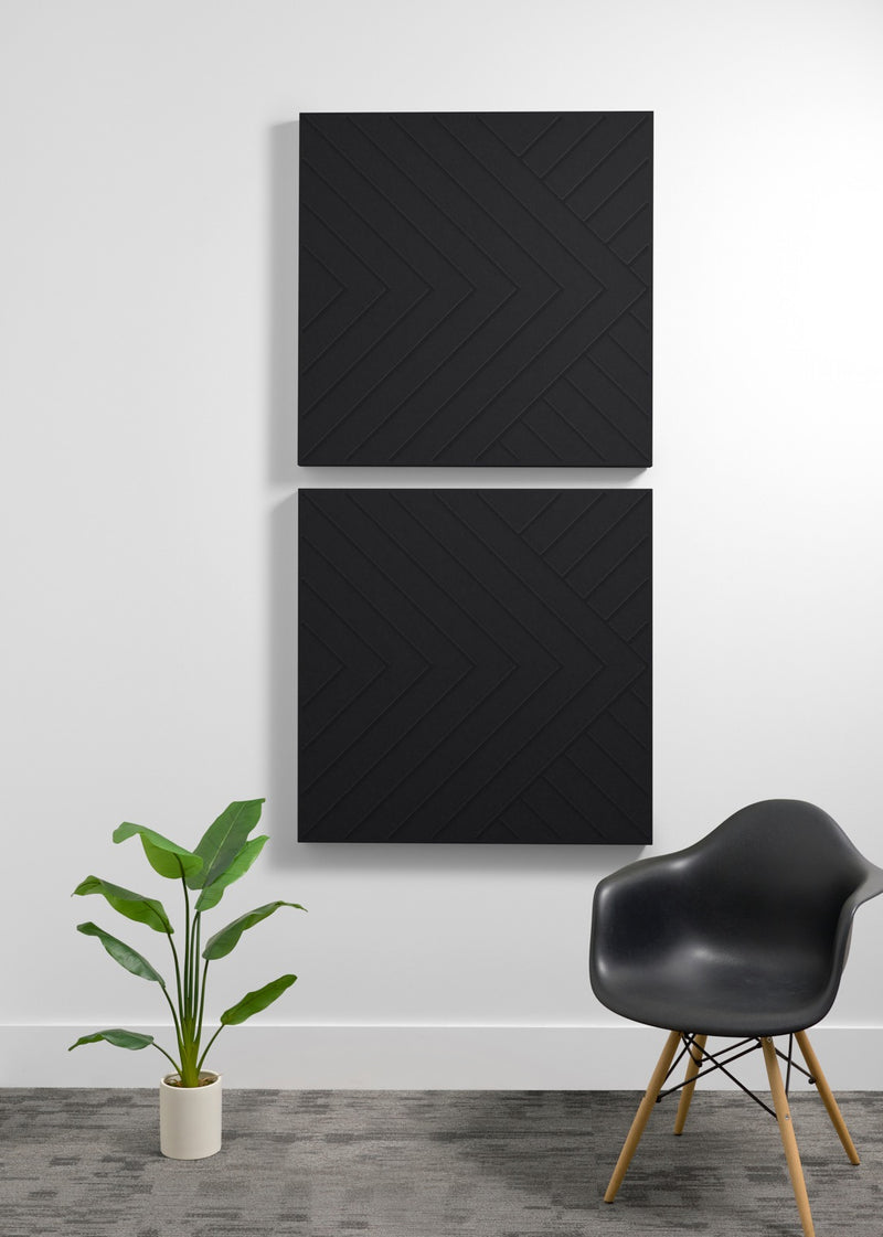 Two black 3D acoustic wall panels with chevron pattern mounted vertically on white wall.