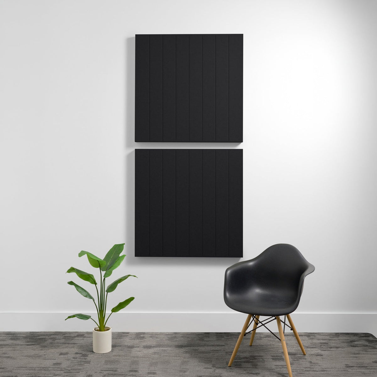 Two stacked black acoustic wall panels with parallel engraved lines mounted on white wall.