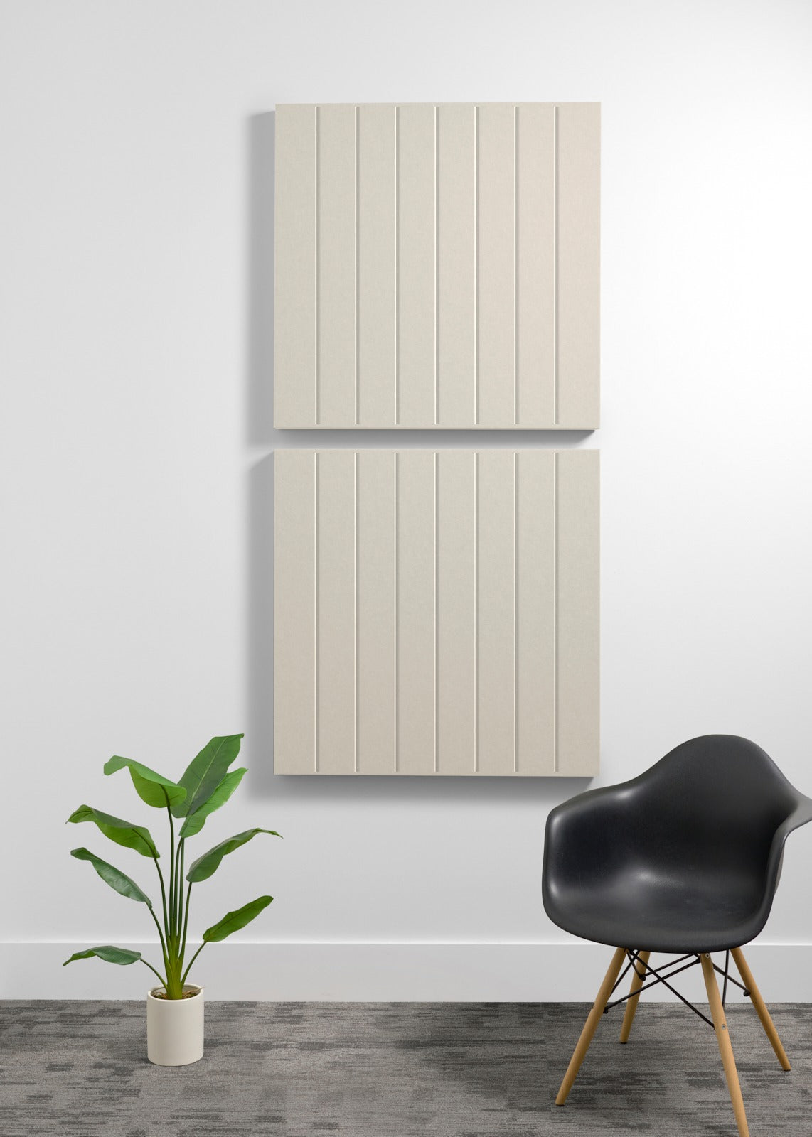 Two large cream-colored acoustic panels with vertical grooves mounted on wall above black chair and potted plant.