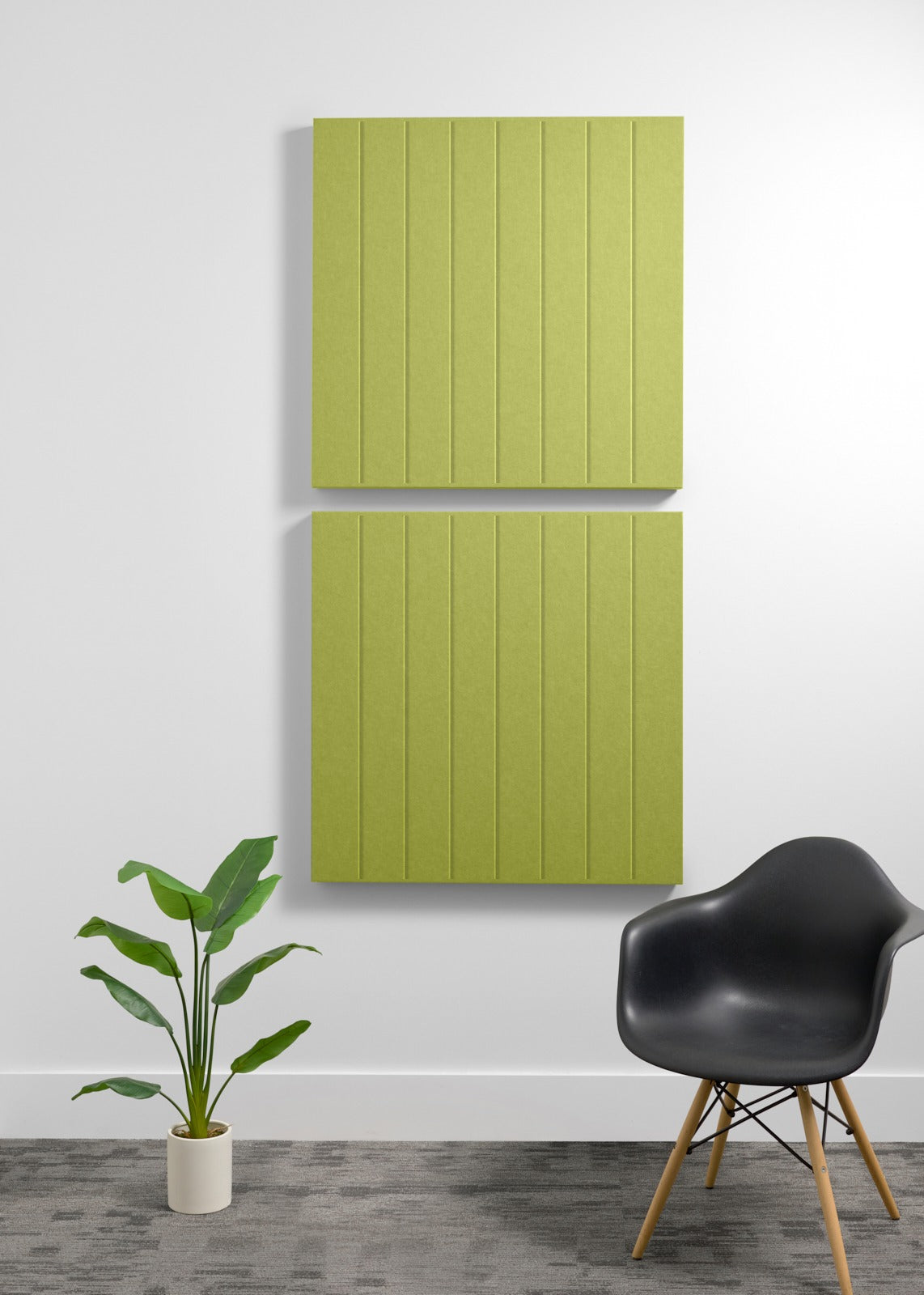 Two lime green acoustic panels with vertical ribbed texture mounted on wall above black chair and potted plant.