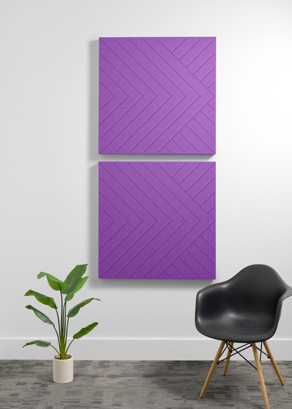 Two purple acoustic panels with chevron pattern mounted on wall above black chair and potted plant.