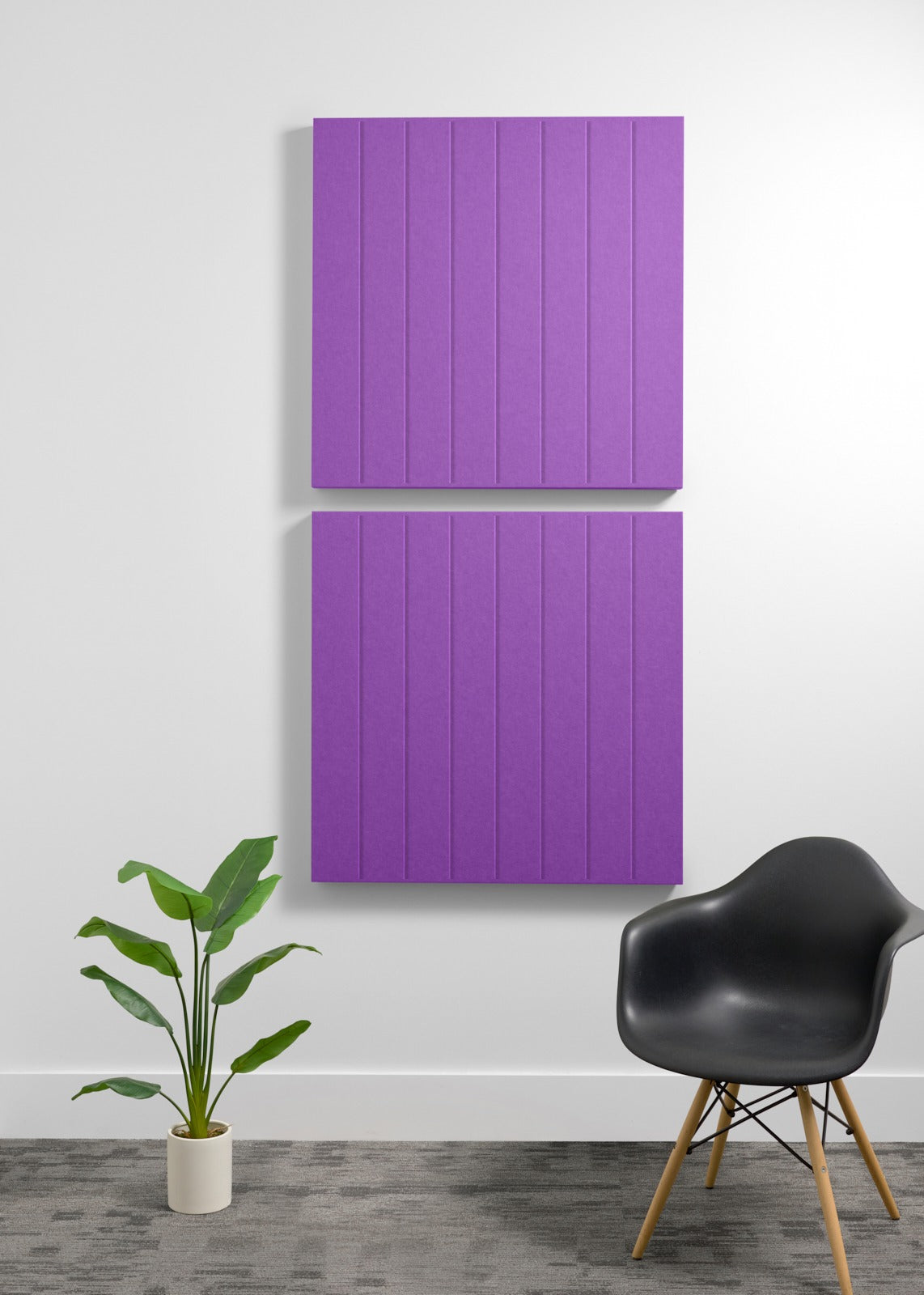 Two purple acoustic wall panels with vertical ribbed texture mounted on white wall above potted plant and black chair.