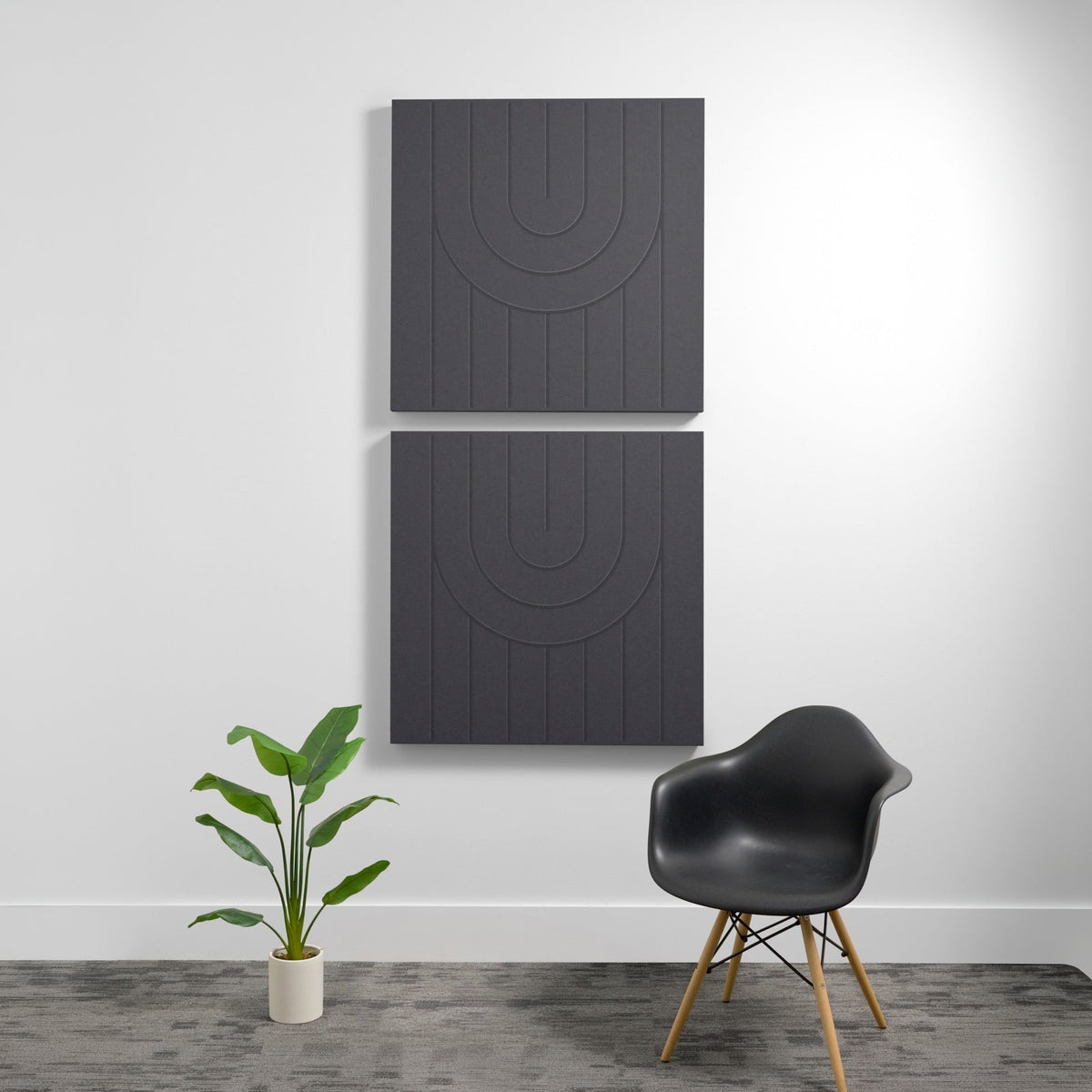 Two dark gray acoustic wall panels with engraved arc pattern designs mounted vertically on white wall.