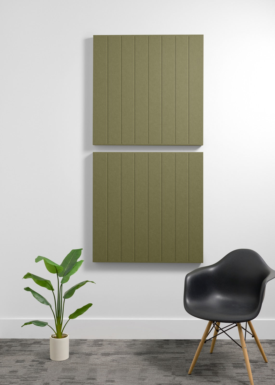 Two stacked olive-green acoustic panels with vertical ribbed texture mounted on wall above chair and plant.
