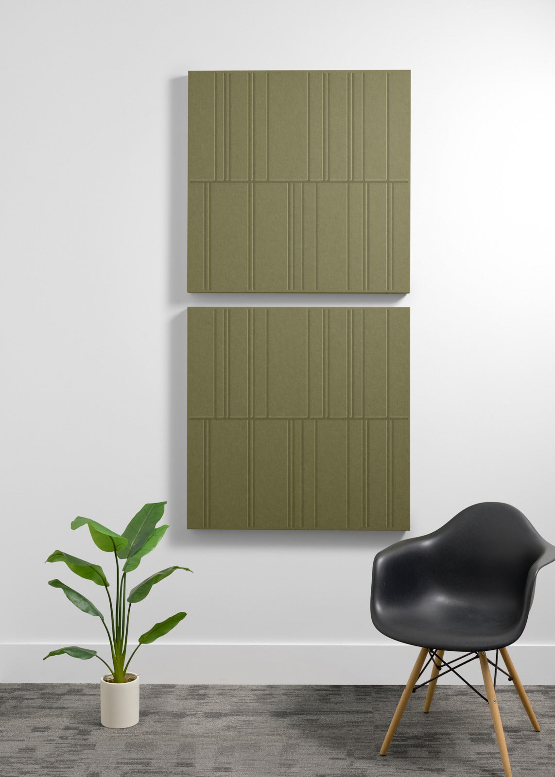 Two large olive-green acoustic wall panels with vertical linear engraved pattern mounted on wall above chair and plant.