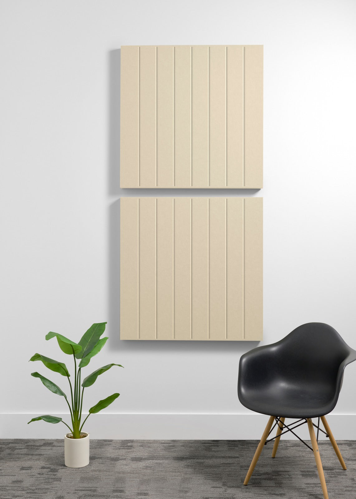 Two large cream-colored acoustic panels with vertical grooves mounted on a wall above a black chair and potted plant.