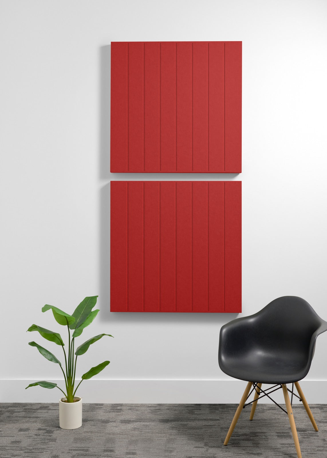 Two red 3D acoustic panels with vertical ribbed texture mounted on wall above black chair and potted plant.