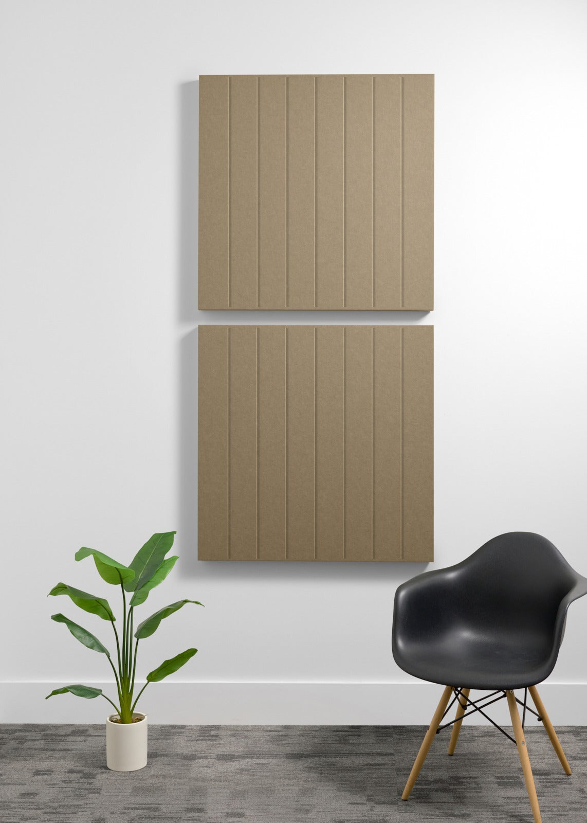 Two large tan acoustic panels with vertical ribbed texture mounted on wall above black chair and potted plant.