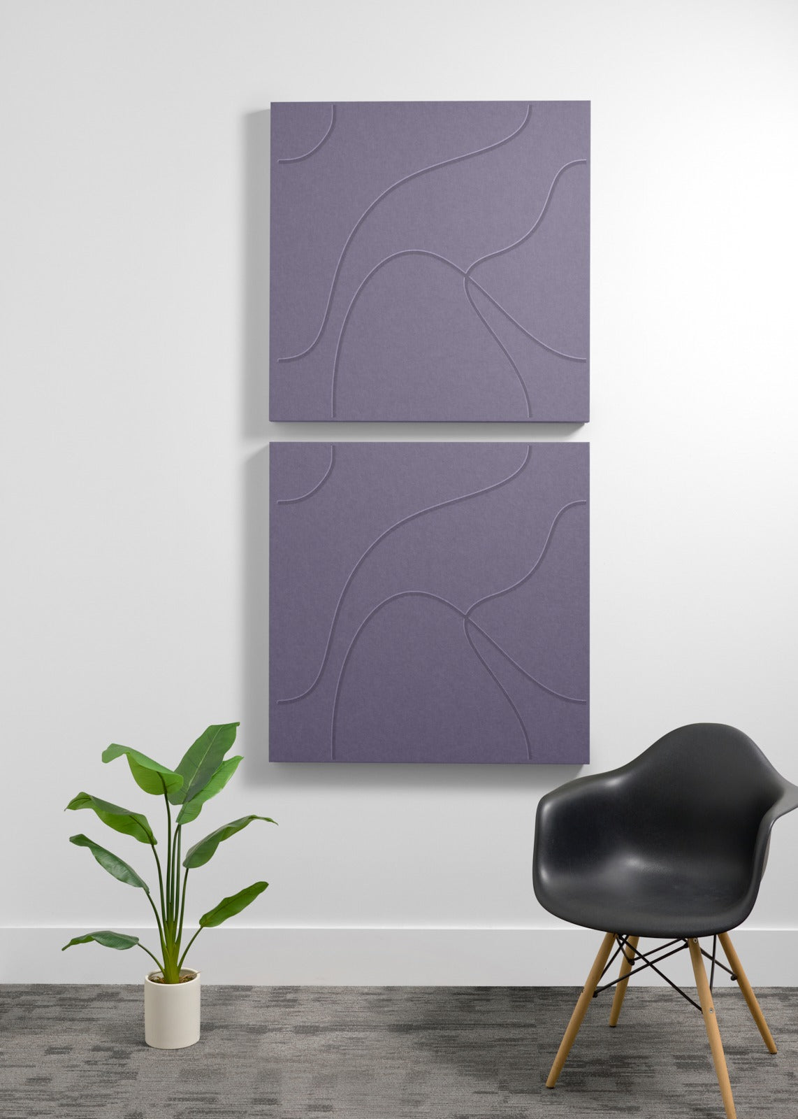Two stacked purple square acoustic panels with engraved wavy line patterns mounted on wall above chair and plant.