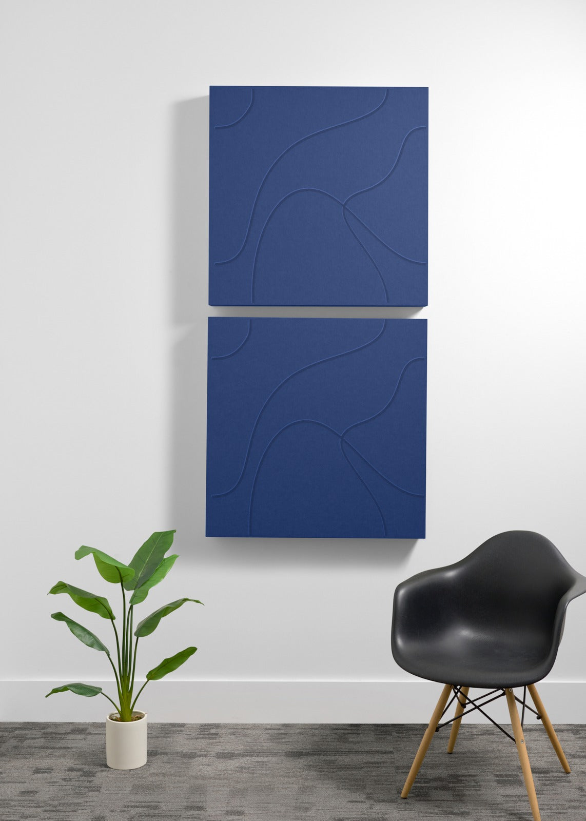 Two stacked navy blue acoustic panels with engraved topographic line patterns mounted on a white wall.