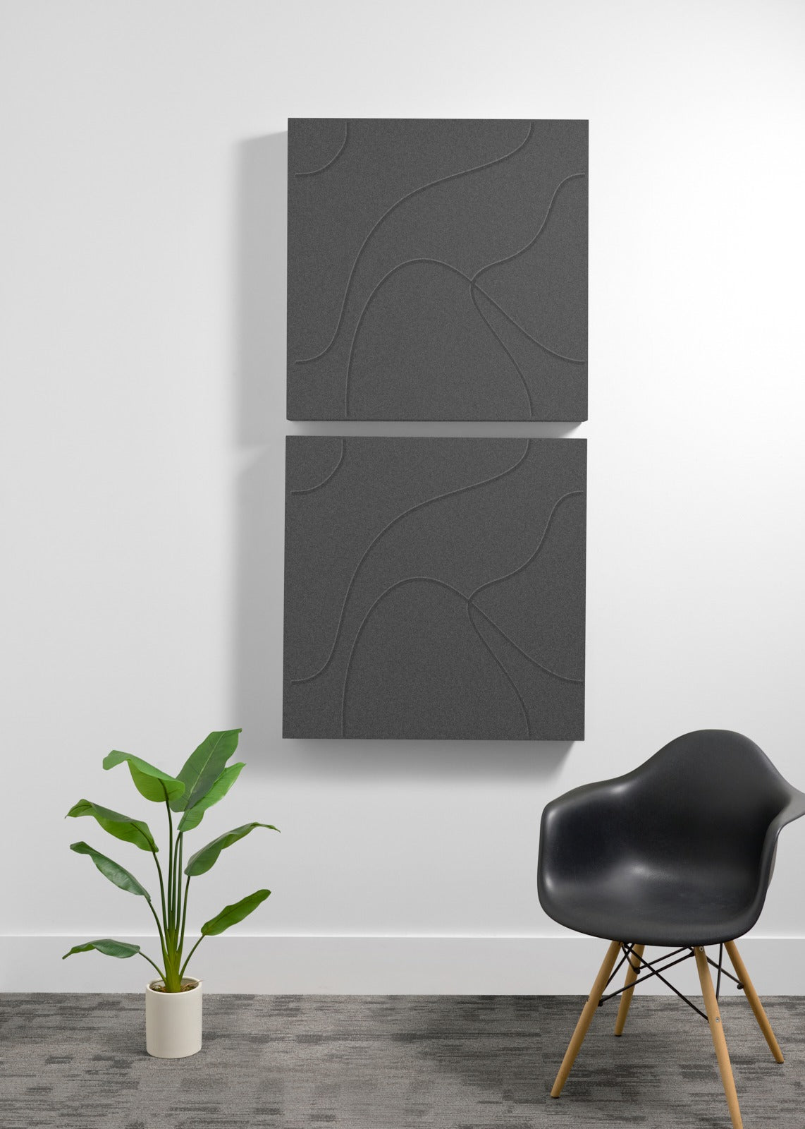 Two stacked dark gray acoustic panels with topographic line engravings mounted on a white wall.