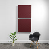 Two burgundy 3D acoustic wall panels with diagonal quilted pattern mounted vertically on white wall.