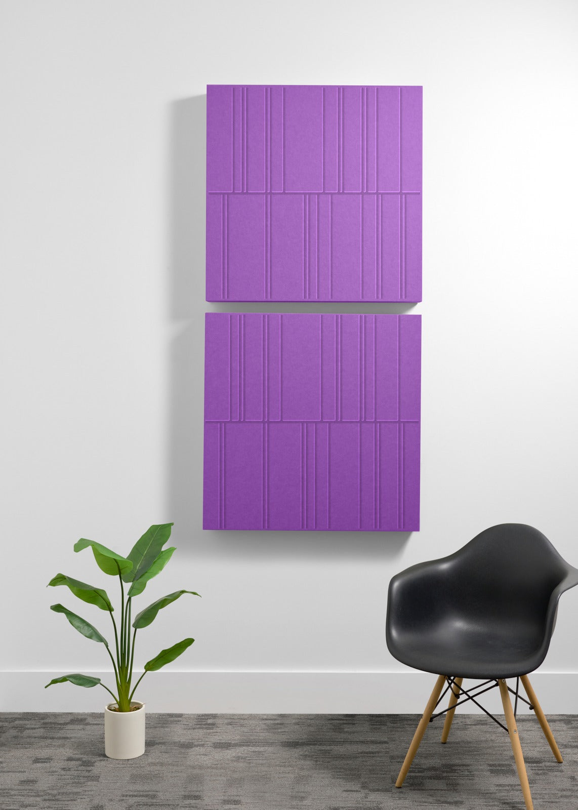 Four purple acoustic panels with engraved linear pattern mounted vertically on white wall above plant and chair.