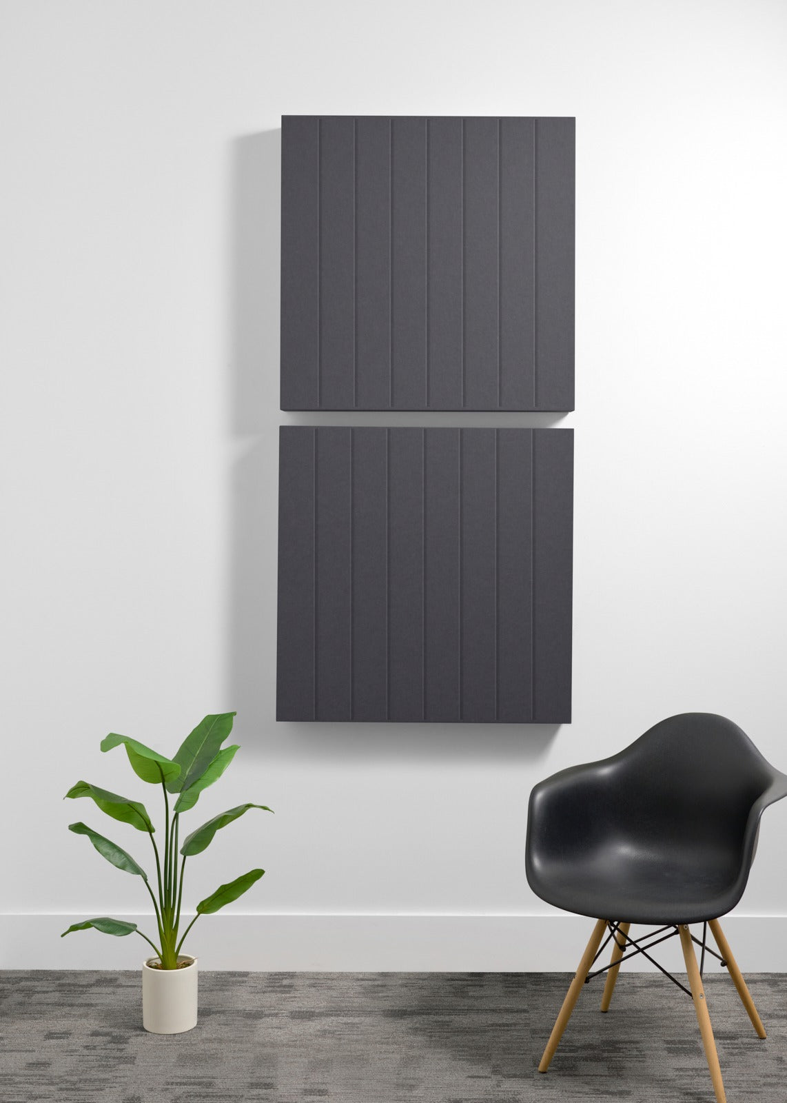 Two stacked dark gray acoustic panels with parallel vertical engraved lines mounted on white wall.