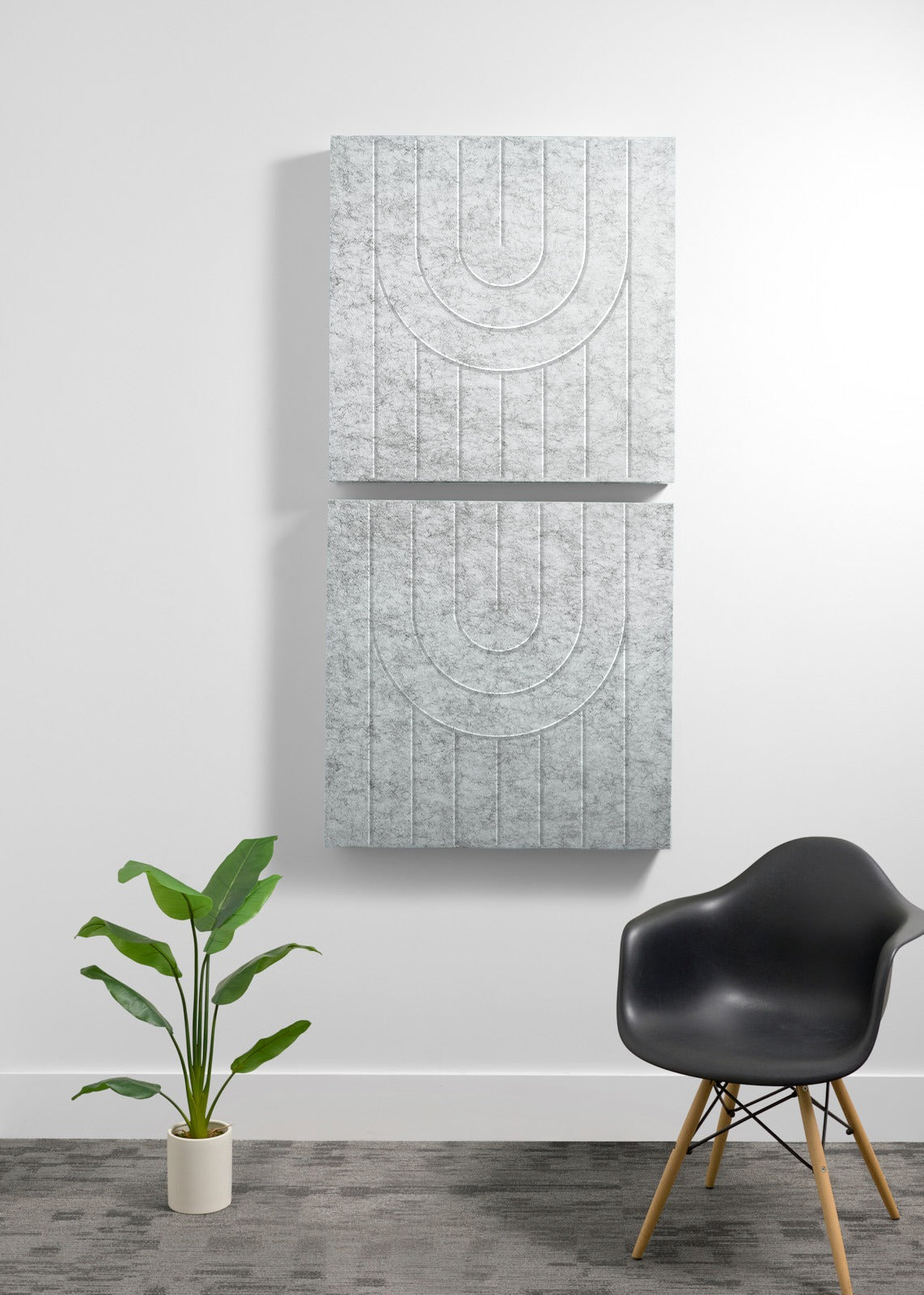 Two stacked light gray acoustic panels with engraved geometric arc patterns and vertical lines on white wall.