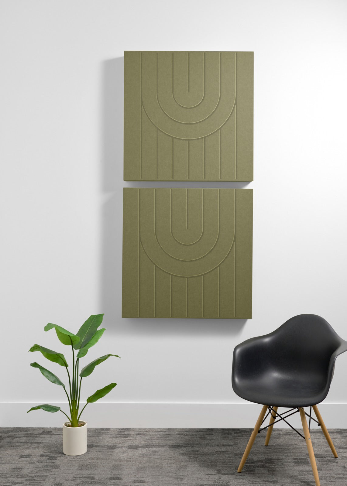 Two sage green square acoustic panels with engraved arc pattern and vertical lines mounted on wall.