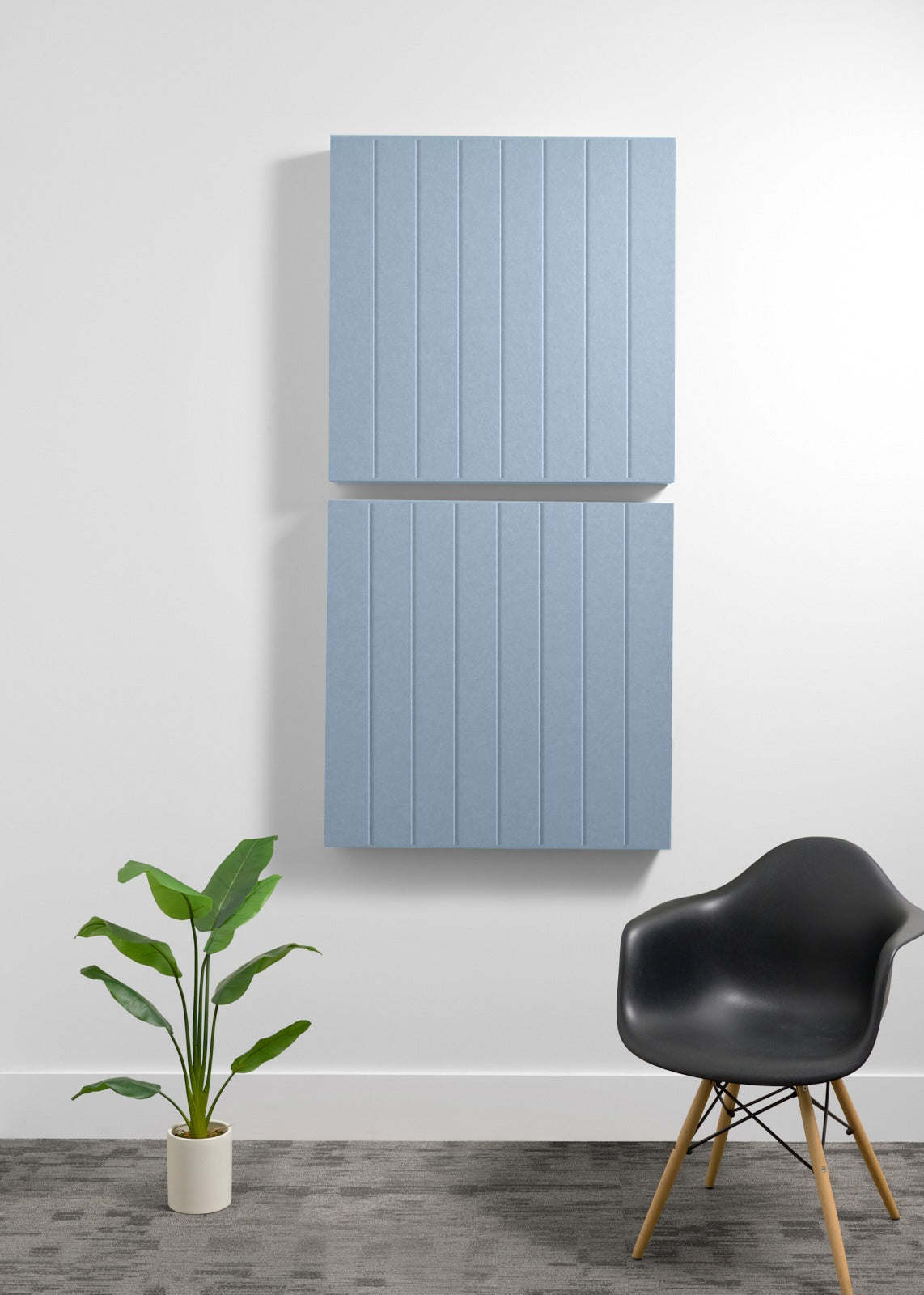 Two stacked blue-gray acoustic panels with parallel vertical engraved lines mounted on white wall.
