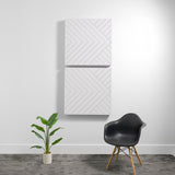 Two white 3D acoustic wall panels with diagonal engraved pattern mounted vertically on a light wall.