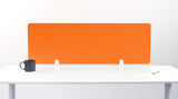 Orange rectangular desk divider with white mounting brackets on white desk surface.