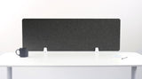 Dark gray fabric desk divider with rounded corners mounted on white desk with two support brackets.