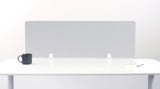 Gray desk divider with white mounting brackets positioned on white desk surface.