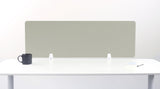 Sage green desk divider panel with white mounting brackets on white desk surface.