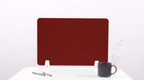 Dark red grid desk divider with rounded corners positioned on white surface next to mug and pens.