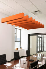 Six orange felt acoustic beams suspended horizontally from ceiling in staggered arrangement above conference table.