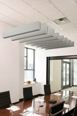 Gray felt acoustic beams suspended from ceiling in conference room above wooden table.